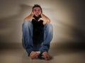 Young desperate and depressed man crying alone sitting at home floor in shady and dramatic studio light looking sad and frustrated Royalty Free Stock Photo