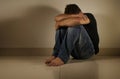 Young desperate and depressed man crying alone sitting at home floor in shady and dramatic studio light looking sad and frustrated Royalty Free Stock Photo