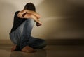 Young desperate and depressed man crying alone sitting at home floor in shady and dramatic studio light looking sad and frustrated Royalty Free Stock Photo