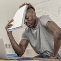 Young desperate and overwhelmed black afro American student man in stress at home working stressed with laptop computer worried an