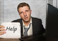 Young desperate and stressed business man working overwhelmed at office computer desk feeling helpless and overworked holding Royalty Free Stock Photo