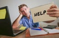 Young desperate and stressed businessman feeling overwhelmed working with laptop computer at office desk sad suffering stress aski Royalty Free Stock Photo