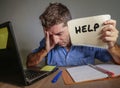 Young desperate and stressed businessman feeling overwhelmed working with laptop computer at office desk sad suffering stress aski Royalty Free Stock Photo