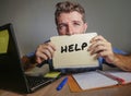 Young desperate and stressed businessman feeling overwhelmed working with laptop computer at office desk sad suffering stress aski Royalty Free Stock Photo