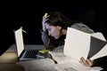 Young desperate university student girl in stress for exam studying with books and computer laptop late at night Royalty Free Stock Photo