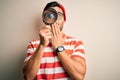 Young detective man looking through magnifying glass over isolated background cover mouth with hand shocked with shame for Royalty Free Stock Photo