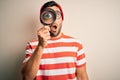 Young detective man looking through magnifying glass over isolated background scared in shock with a surprise face, afraid and Royalty Free Stock Photo
