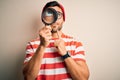 Young detective man looking through magnifying glass over isolated background serious face thinking about question, very confused Royalty Free Stock Photo