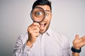 Young detective man looking through magnifying glass over isolated background very happy and excited, winner expression Royalty Free Stock Photo