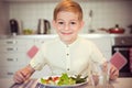 Young diligent boy at a table eating healthy meal with cutlery Royalty Free Stock Photo