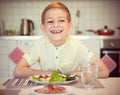 Young diligent happy boy at a table eating healthy meal with cu