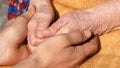 A young dirty working male hands comforting an elderly pair of hands of grandmother outdoor close up. Royalty Free Stock Photo