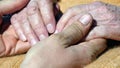 A young dirty working man`s hands comforting an elderly pair of hands of grandmother outdoor Royalty Free Stock Photo