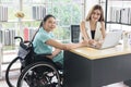 Young disabled Asian businesswoman working together with her colleague in office Royalty Free Stock Photo