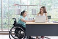 Young disabled Asian businesswoman working together with her colleague in office Royalty Free Stock Photo