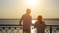 Young disabled couple looks at river at back sunset light