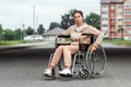 A young disabled girl sits in a wheelchair on the street. The concept of a wheelchair, disabled person, full life, paralyzed, Royalty Free Stock Photo
