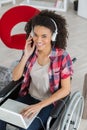 Young disabled girl in wheelchair using laptop and headphones