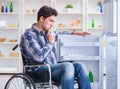 Young disabled injured man opening the fridge door Royalty Free Stock Photo