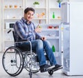 Young disabled injured man opening the fridge door Royalty Free Stock Photo