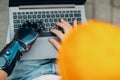 Young disabled man with artificial prosthetic hand using typing on laptop computer keyboard.