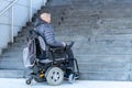Young disabled man in a electric wheelchair in front of stairs
