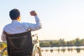 Young disabled man with field background.He is wearing a hat and sitting on wheelchair.He is looking into river Royalty Free Stock Photo