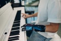 Young disabled man play on piano electronic synthesizer with artificial prosthetic hand in music shop.