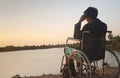 Young disabled man with river background.He is sitting on wheelchair and looking into river Royalty Free Stock Photo