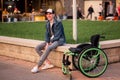 a young disabled man sits next to a wheelchair and shows her the middle finger Royalty Free Stock Photo