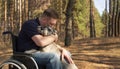 A young disabled man in a wheelchair and a dog in the park