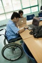 A young disabled student doing his homework on a computer, in a classroom