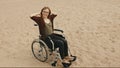Young disabled woman on the sandy beach sitting in the wheelchair