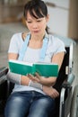 young disabled woman in wheelchair with book Royalty Free Stock Photo