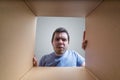 Young disappointed man is looking on gift inside cardboard box Royalty Free Stock Photo