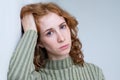 Young disappointed woman with red curly hair