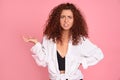 Young displeased redhead girl gesturing looking at camera. Confused girl arguing with a boyfriend. Pink background Royalty Free Stock Photo