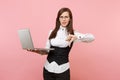 Young dissatisfied business woman in suit, glasses working in laptop showing thumb down on pastel pink Royalty Free Stock Photo