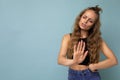 Young dissatisfied sad attractive winsome blonde curly woman with sincere emotions wearing trendy black top isolated