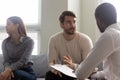 Young dissatisfied woman getting bored while husband talking with psychologist.