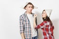 Young dissatisfied woman, man in casual clothes and newspaper hats quarrelling. Couple isolated on white background