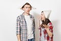 Young dissatisfied woman, man in casual clothes and newspaper hats quarrelling. Couple isolated on white background