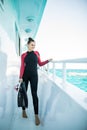 Young diver girl in black wetsuit standing on board of the yacht