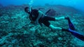 Young diver slowly move horizontally - exercising buoyancy at scuba courses. Drifting above sea bottom with many dead corals
