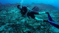 Young diver slowly move horizontally - exercising buoyancy at scuba courses. Drifting above sea bottom with many dead corals Royalty Free Stock Photo