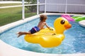 Young diverse little boy jumping onto a large inflatable pool toy in a backyard swimming pool on a warm summer day. Royalty Free Stock Photo