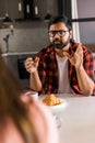 Young diverse loving couple eating croissant and talks together at home in breakfast time. Communication and