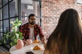 Young diverse loving couple eating croissant and talks together at home in breakfast time. Communication and