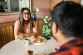 Young diverse loving couple eating croissant and talks together at home in breakfast time. Communication and