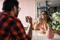 Young diverse loving couple eating croissant and talks together at home in breakfast time. Communication and